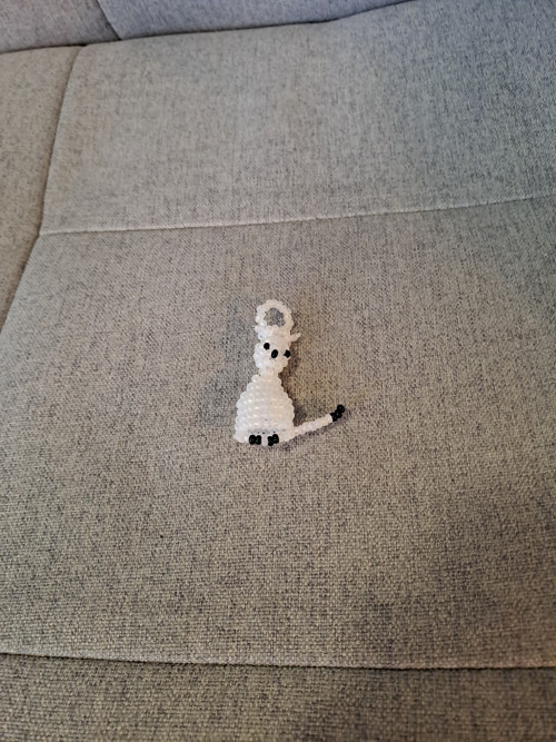 Kočka z korálků, matně bílà.